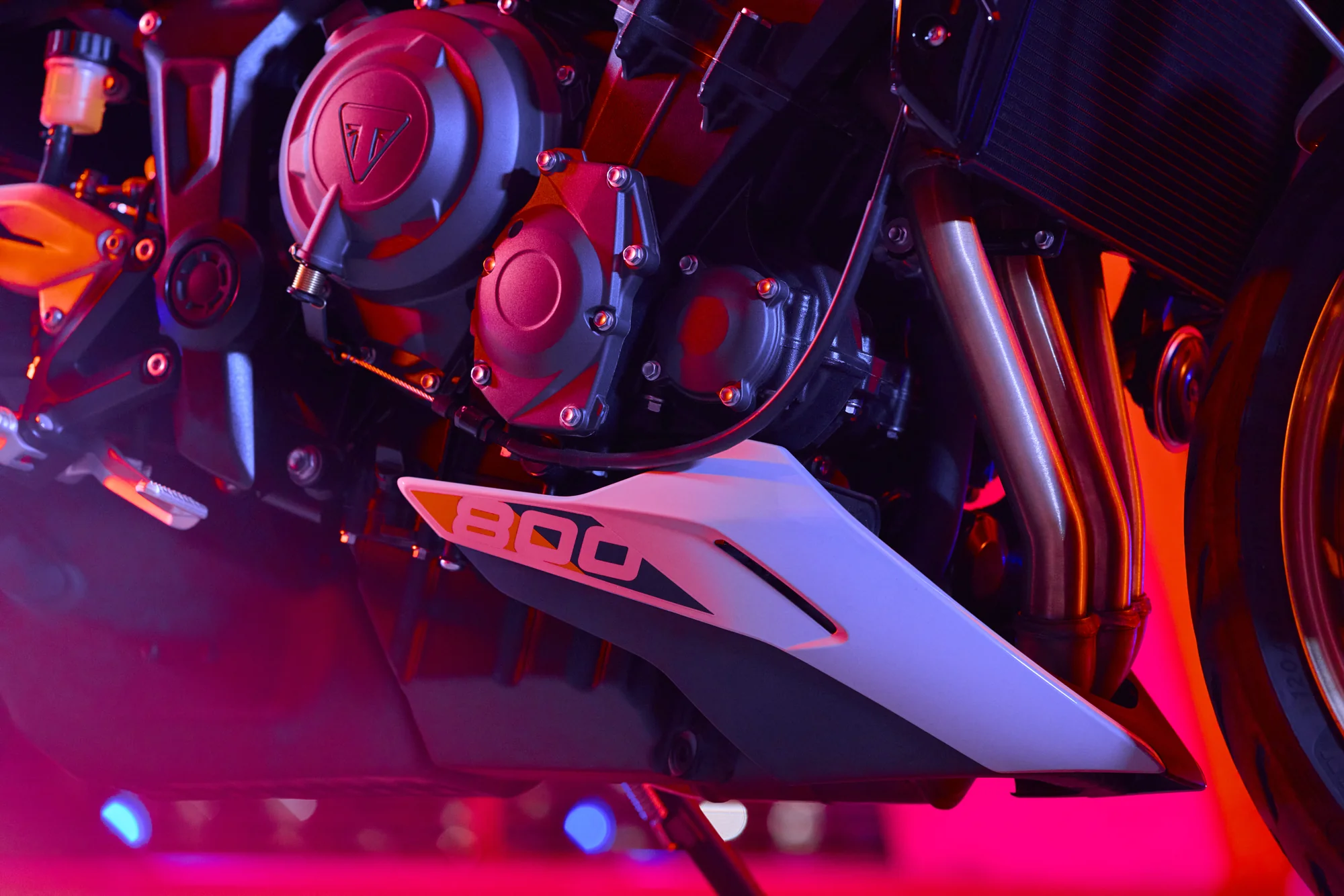 Detalle del motor tricilíndrico de la Triumph Trident 800 bajo iluminación roja y azul