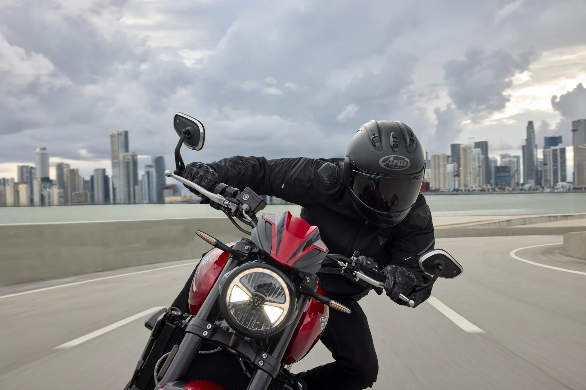 Piloto inclinado sobre una Triumph Trident 800 roja durante una curva
